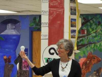 volunteer holding up an LED bulb in front of group of seated attendees