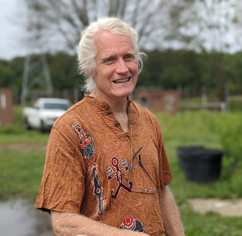 photo of smiling man with longish white hair wearing a brown shirt