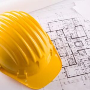 yellow hardhat on top of papers of building plans