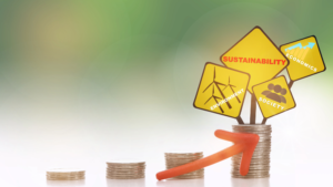 four stacks of coins with yellow diamond-shaped signs reading sustainability, economy, sticking out from the top.
