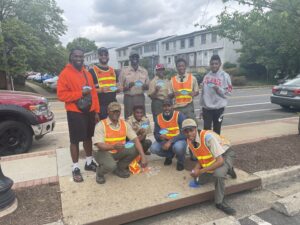 image of a group of volunteers in orange safety vests pose in front of storm drain marker that they have placed on a curb in Arlington