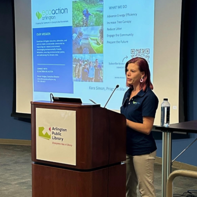 Kara Simon, EcoAction Arllington program manager speaks from behind the podium with a screen projected behind her.