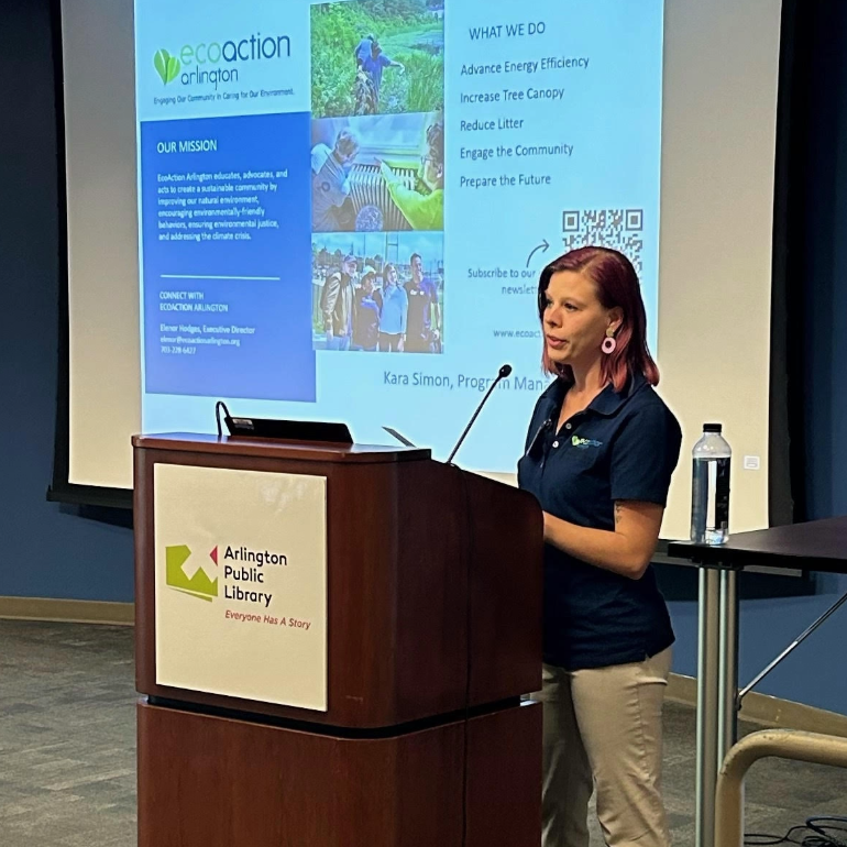 Kara Simon, EcoAction Arllington program manager speaks from behind the podium with a screen projected behind her.