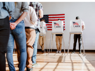 Elections Matters a line of voters wait to vote behind the privacy screens with the American flag printed on them