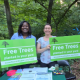 Kisha Sungoro, Outreach Manager and Sarah Foard, Tree Ambassador holding up green signs that read: Free Trees, promoting EcoAction Arlington's Tree Planting Program