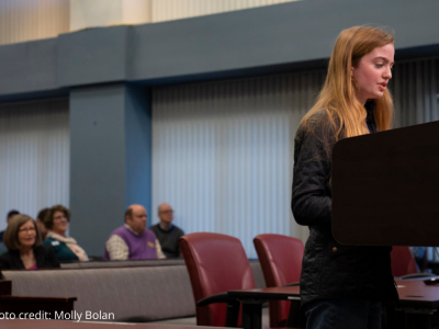 2025-Climate resolution-14 photo of student rep speaking at podium to Arlington County Board with attendees seated behind them.