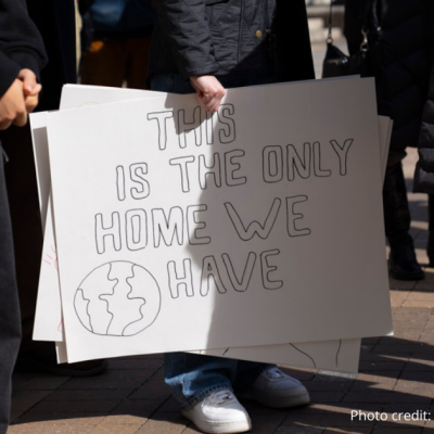 Photo close up of sign at the rally on 2/22/2025 with attendees legs seen around the sign. Sign reads: Tis sis the only Home we have in large black block letters.