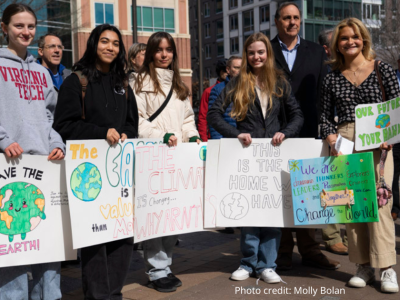2025-Climate Resolution-16 Photo: crowd at the 2/22/2025 rally with five females in the front smiling and holding signs that read: 1. Save the earth with an anamorphic earth, 2. sign is obscured, 3. The Climate is changing Why Aren't (blocked by next sign, 4. This is the Home we Have, 5. We are dreamers, thinkers, explorers, leaders, creators and together we can change the world, Our Future, Your Hands. Photo credit: Molly Bolan.