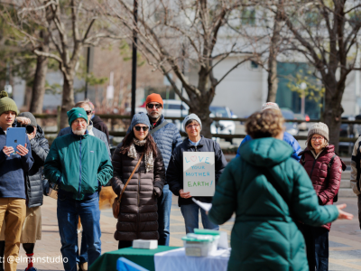 2025-Climate Resolution-8 Back of a speaker in teal winter parka addressing the crowd at the rally on 2/22/2025, photo credit: @elmanstudio