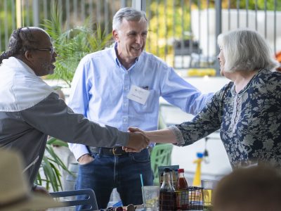 Bill Campbell shakes hands with woman as another man welcomes them