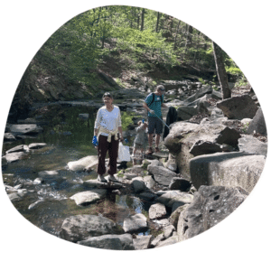 two volunteers and small child standing in stream with trash bags