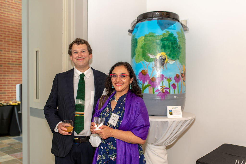 a man and woman posing in front of a painted rain barrel