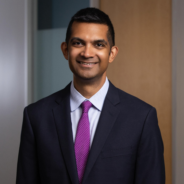 headshot of Vikram Sinha a man with short dark hair wearing a dark shit, dress shirt and deep purple tie smiling at the camera