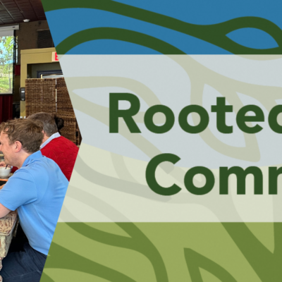 banner graphic with dark green background for a luncheon at Busboys & Poets Shirlington on Thursday, February 11, 2027 on the right is green and blue abstract leaf-like background with the bold text “Rooted In Our Community” centered across the image. On the right a photo of people sitting at tables with plates and glasses in front of them, with a colorful illuminated screen in the background depicting trees.