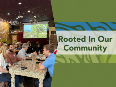 banner graphic with dark green background for a luncheon at Busboys & Poets Shirlington on Thursday, February 11, 2027 on the right is green and blue abstract leaf-like background with the bold text “Rooted In Our Community” centered across the image. On the right a photo of people sitting at tables with plates and glasses in front of them, with a colorful illuminated screen in the background depicting trees.